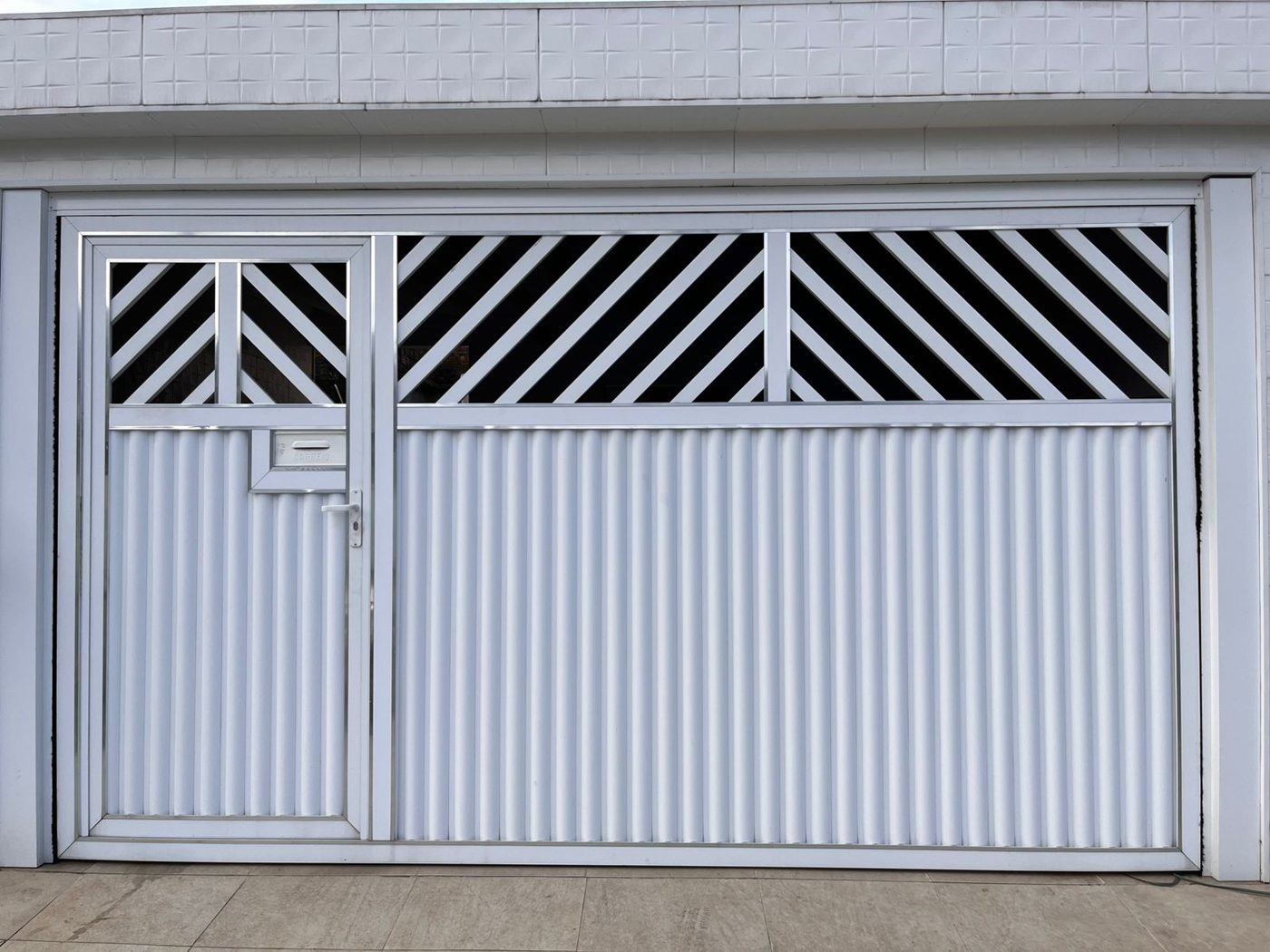 Portão nº 33: Basculante branco com grades na diagonal, porta social embutida e frisos brilhantes